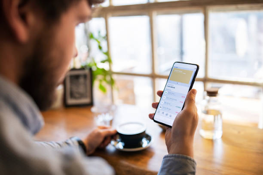 Person using a smartphone app in a bright cafe, reflecting the growth of the mobile app development market.