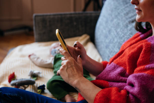 A person using a smartphone on a couch, symbolizing the growing use of mobile apps in everyday life.